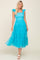 woman wearing a bright turquoise tiered tulle dress with ruffle straps and a smocked bodice