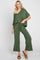 woman wearing a green off-the-shoulder jumpsuit with wide-leg pants and a drawstring waist, styled casually with sandals