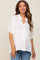 woman wearing a white oversized maternity button-up shirt with short sleeves and a relaxed fit, smiling at the camera