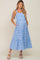woman wearing a blue and white gingham maternity dress with a tiered skirt and tie straps, showcasing her baby bump