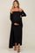 woman wearing a black ribbed off-shoulder maternity dress with a side slit and holding her baby bump