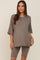 woman wearing a brown oversized maternity top with a front pocket and matching biker shorts
