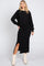 woman wearing a black cropped sweatshirt and a black midi skirt with a side slit, paired with white cowboy boots