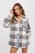 woman wearing a grey and brown plaid flannel shacket over a white top and denim shorts