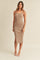 Woman wearing a tan ribbed midi dress with spaghetti straps and a side slit against a neutral background