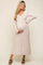 woman wearing a light beige ribbed long sleeve maternity dress and holding her baby bump
