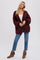 woman wearing oversized maroon chunky knit cardigan with blue jeans and brown fringe ankle boots
