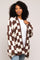 woman wearing a brown and cream checkered oversized cardigan over a white top and light blue jeans
