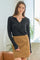 woman wearing a black long sleeve shirt with buttons and a tan suede mini skirt