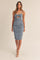 woman wearing a fitted blue ruched midi dress with a twist front and spaghetti straps