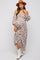 woman wearing a floral off-the-shoulder maternity dress with long sleeves and white cowboy boots, holding her baby bump