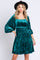 woman wearing a teal velvet dress with puff sleeves and a square neckline, standing against a white background