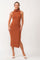 woman in a rust-colored knit midi dress with a mock neck and side slit, wearing white heeled sandals