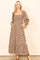 woman wearing a brown floral maxi dress with a square neckline and long sleeves, standing with hands in pockets