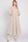woman wearing a cream floral maxi dress with long sleeves and pockets, styled with beige ankle boots