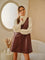 woman wearing a brown leather faux slip dress over a cream turtleneck sweater in a soft indoor setting