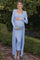 woman wearing a light blue ribbed maternity dress and long cardigan, holding her baby bump outdoors