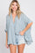 woman wearing a blue and white striped oversized button-up shirt with a relaxed fit and distressed denim shorts