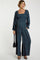 woman wearing a dark floral maternity jumpsuit with a square neckline and long sleeves, holding a black handbag