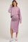 woman wearing a lavender maternity crop top and matching midi skirt with a side slit, showcasing her baby bump