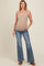 woman wearing a beige maternity tank top and flared jeans, holding her baby bump