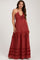 woman wearing a rust red maternity maxi dress with ruffle details and a halter neckline, showcasing her baby bump
