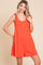 woman wearing a bright orange sleeveless romper with tie shoulder details and a relaxed fit