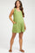 woman wearing a green maternity romper with tie straps and pockets, showcasing her baby bump