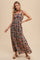 woman wearing a black floral maxi dress with thin straps and a fitted bodice, standing against a neutral background