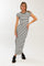 woman wearing a black and white striped maxi dress with short sleeves and side slits, posing with one hand on her hip