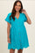 woman wearing a turquoise maternity dress with short sleeves, buttons down the front, and eyelet details