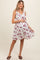 woman wearing a white floral maternity dress with a wrap design and adjustable straps, highlighting her baby bump