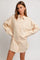woman wearing an oversized beige button-up shirt with a pocket and rolled-up sleeves