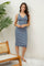 woman wearing a blue ribbed midi dress with a scoop neckline and button details, standing against a white background