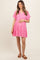 woman wearing a bright pink maternity dress with a tiered design and holding her baby bump