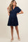woman wearing a navy blue short sleeve maternity dress with a tiered skirt and collar, showing her baby bump