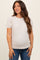 woman wearing a striped beige and cream maternity top with puff sleeves and smiling while standing against a neutral background