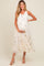 woman wearing a cream floral embroidered maternity dress and holding her baby bump