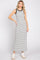 woman wearing a sleeveless black and white striped maxi dress with white platform sneakers