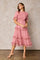 woman wearing a pink midi dress with ruffle details and puff sleeves standing against a neutral background