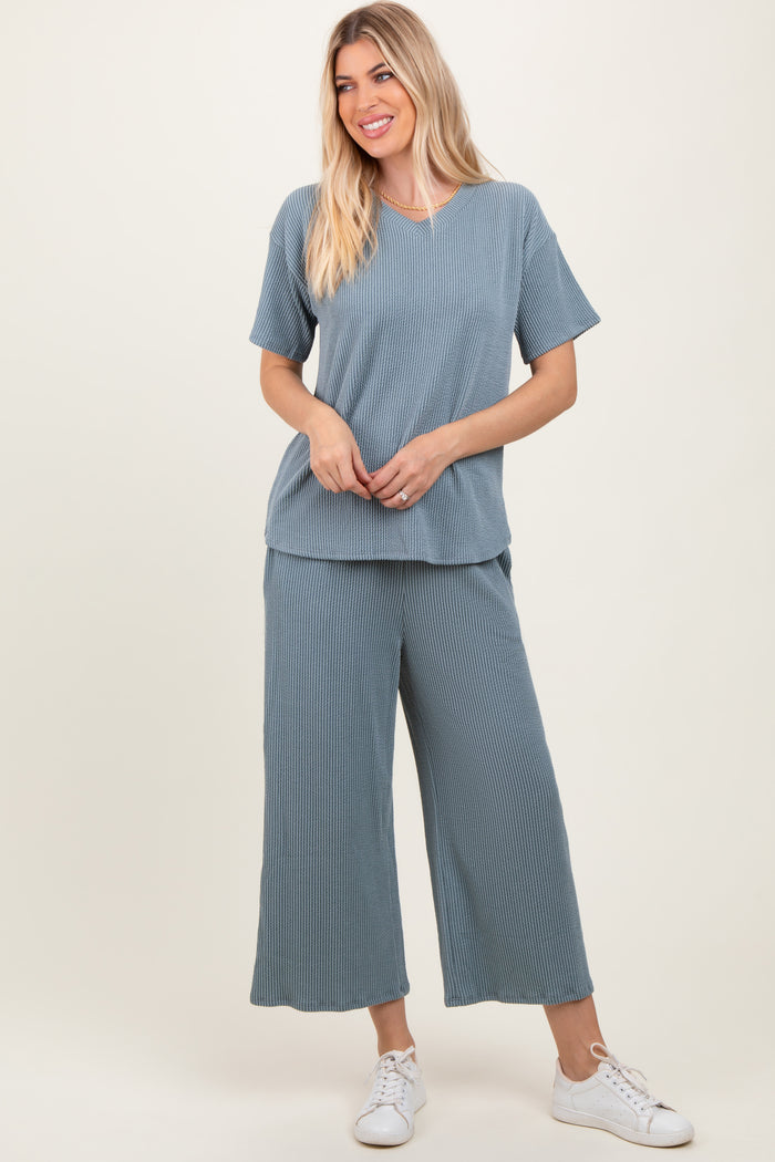woman wearing a light blue textured v-neck top and matching wide-leg pants with white sneakers