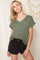 woman wearing an olive green v-neck t-shirt with a pocket and black distressed shorts