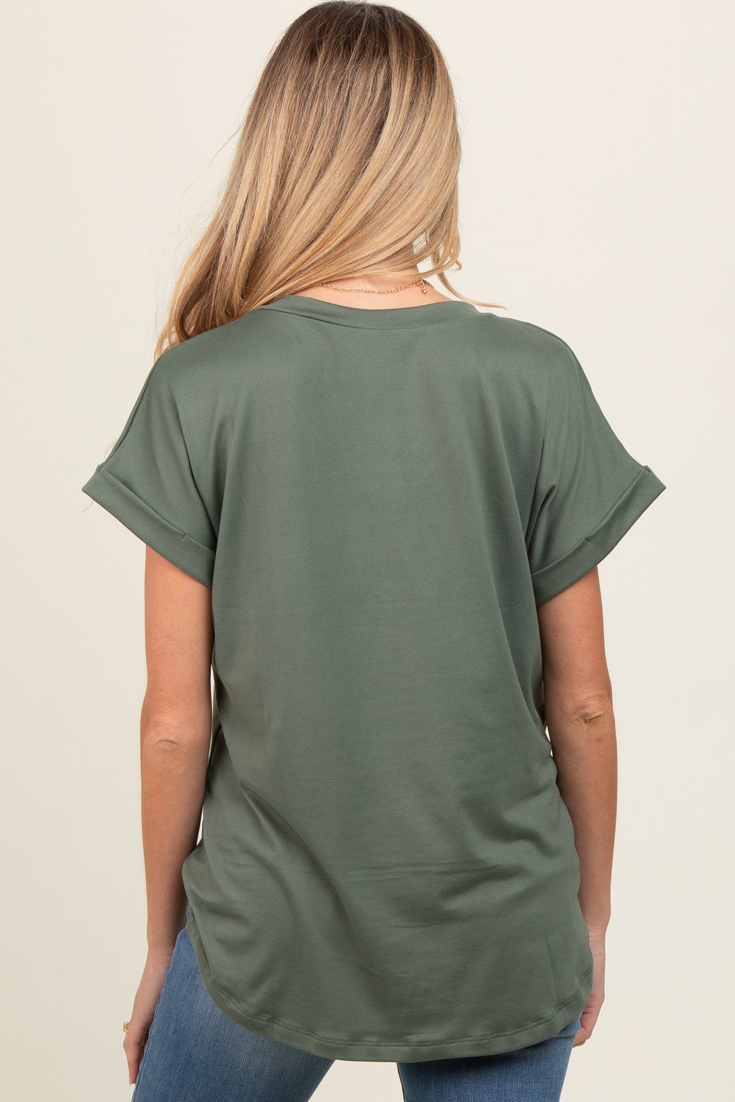 woman wearing a dark green short sleeve maternity top, showing a relaxed fit from the back