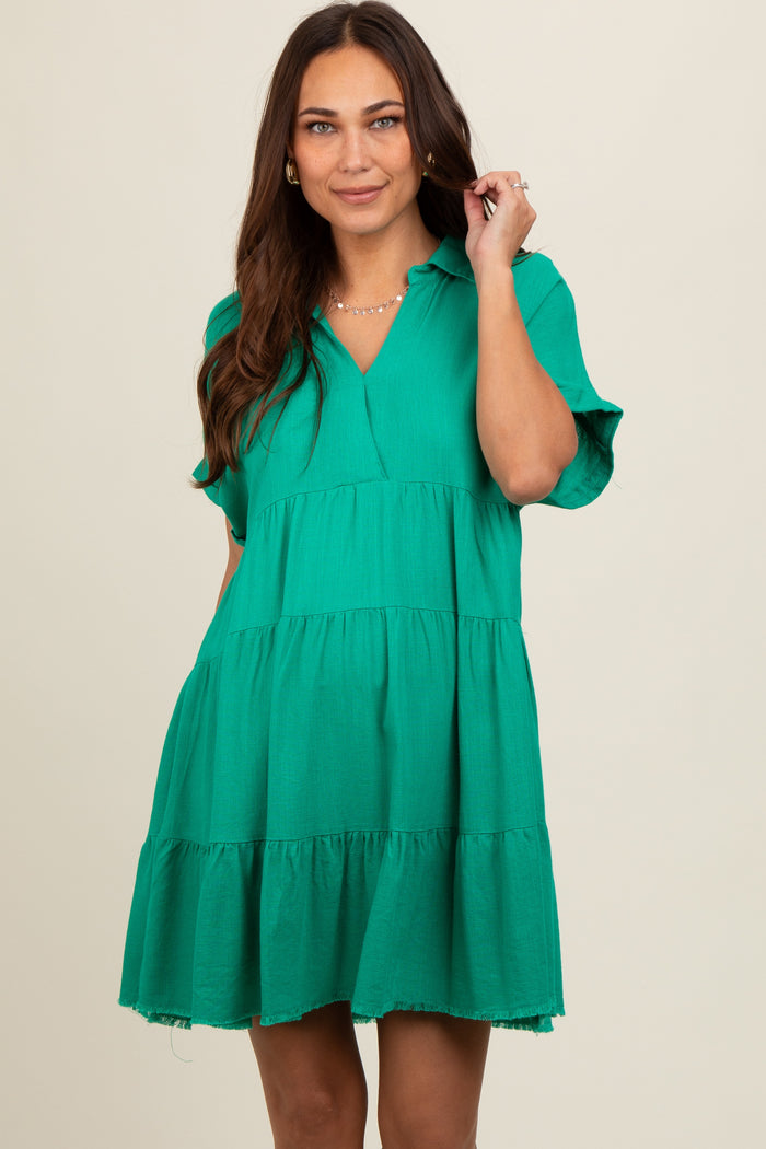 woman wearing a green tiered maternity dress with short sleeves and a v-neckline, smiling at the camera