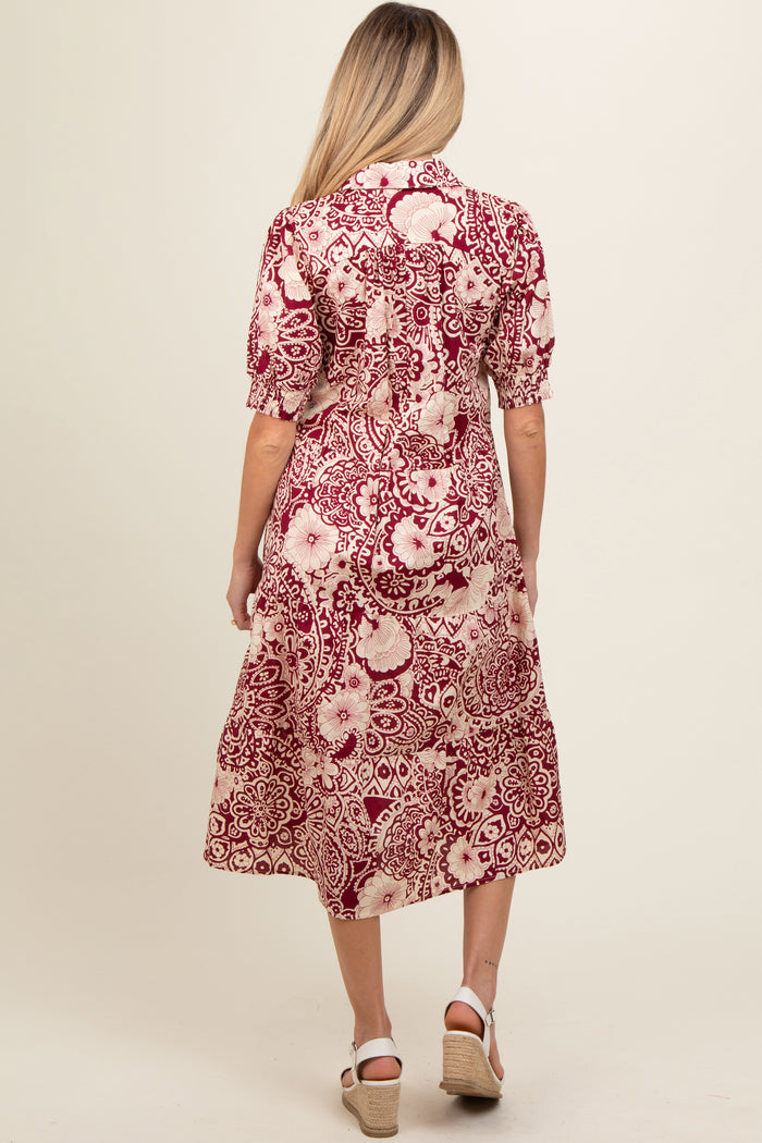 woman wearing a burgundy and cream floral print maternity dress with short sleeves and a midi length