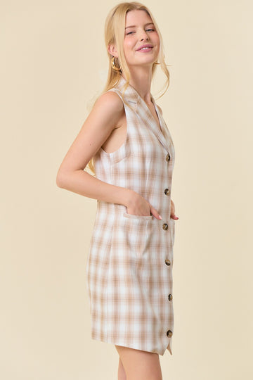 woman wearing a beige plaid sleeveless dress with button details and side pockets