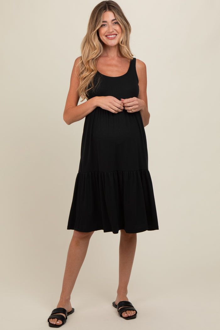 woman wearing a black maternity sundress with a tiered skirt and a visible baby bump