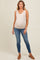 woman wearing a beige maternity tank top and blue skinny jeans, showing her baby bump