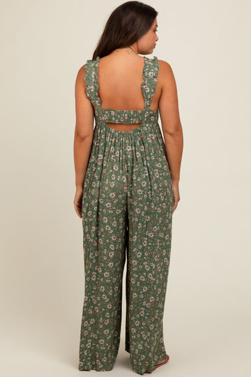 woman wearing a green floral maternity jumpsuit with ruffled straps and an open back