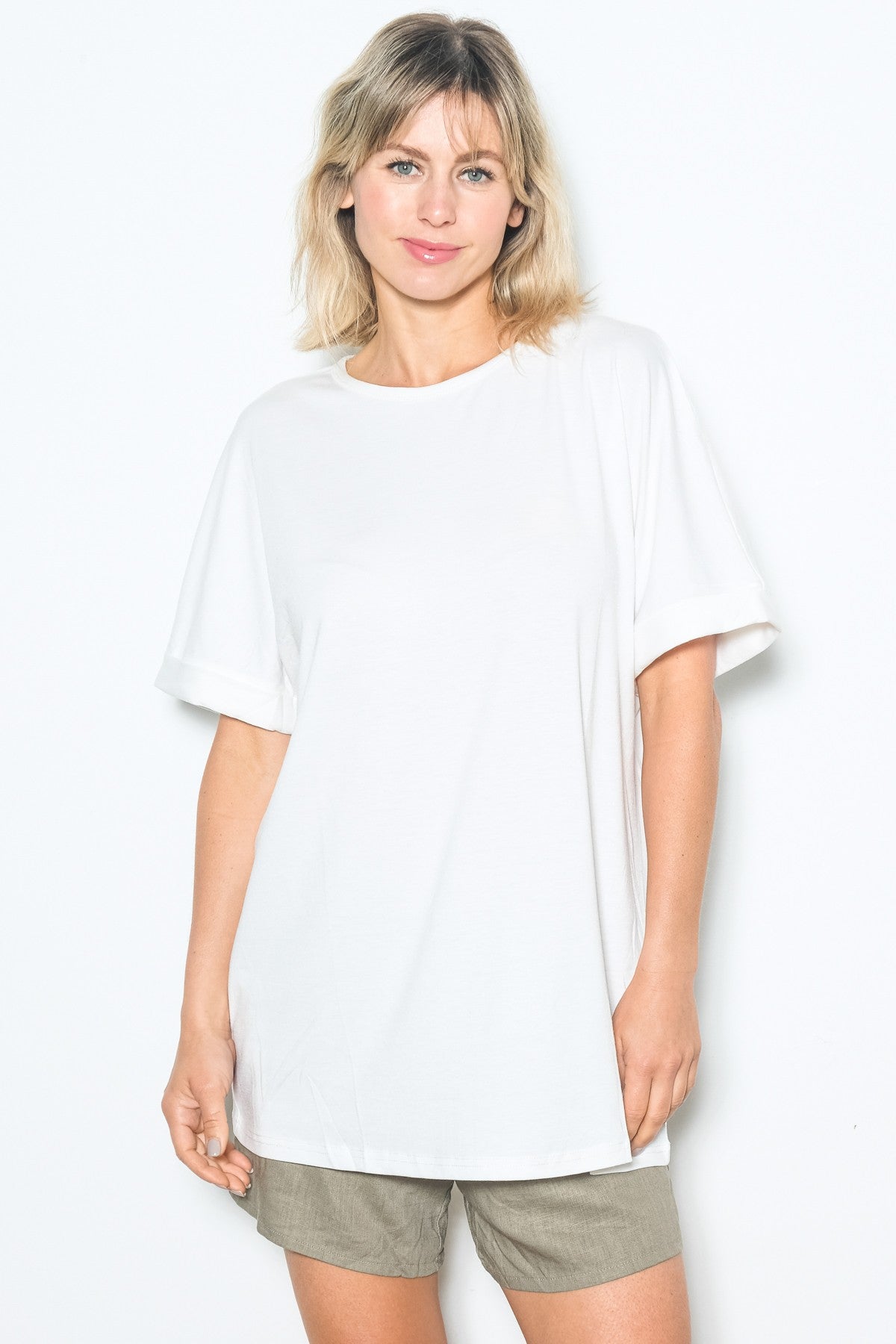 woman wearing a white oversized t-shirt with rolled short sleeves and light brown shorts